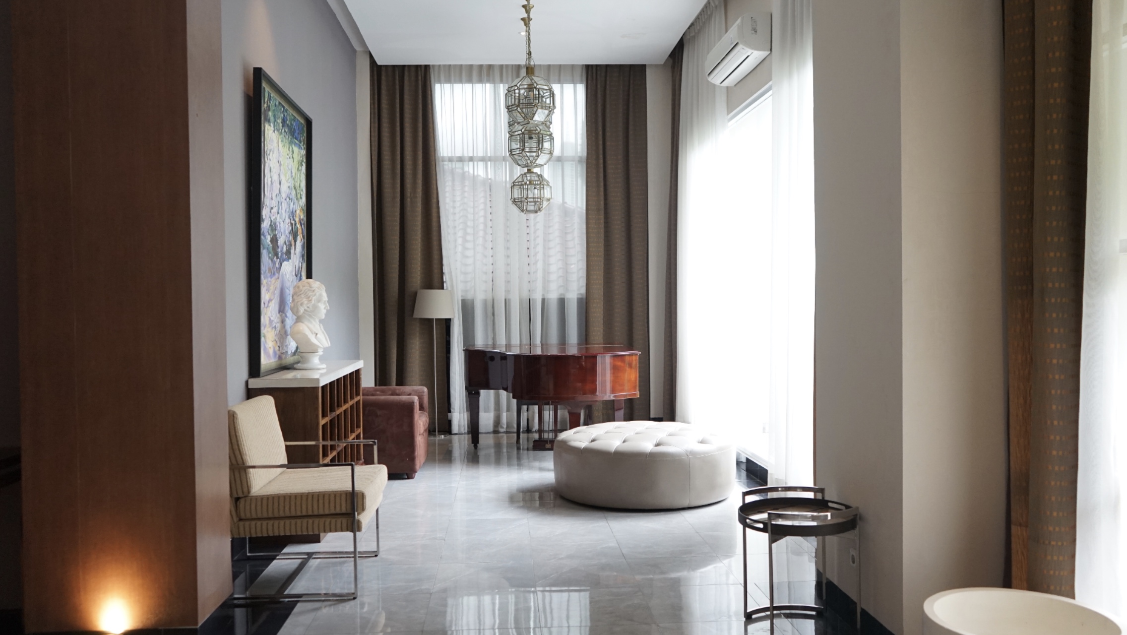  A living room with a piano, a sitting area, and a large window with a view of the city.
